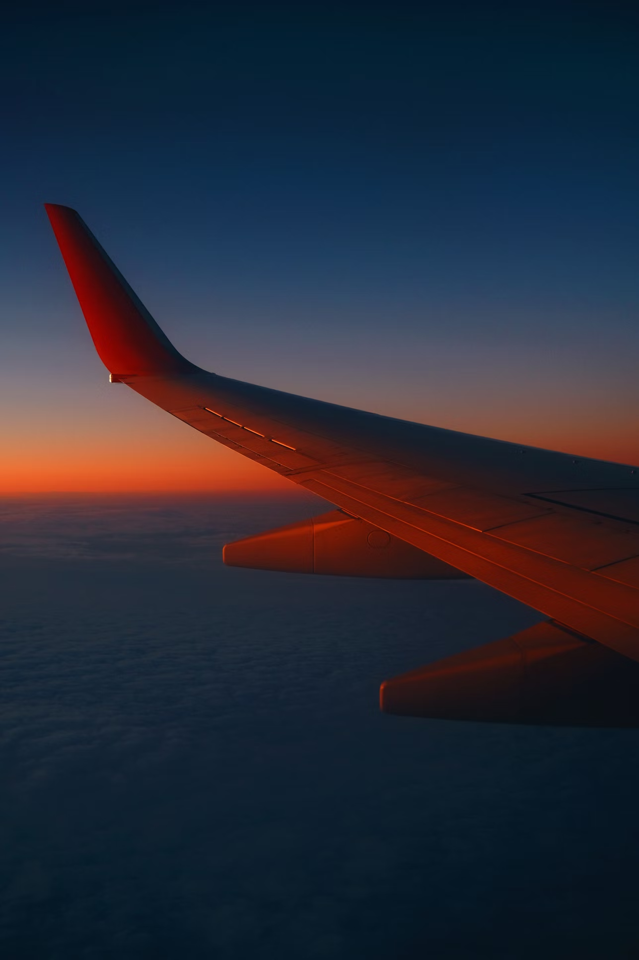View of a serene sunset from an airplane window, looking over the wing.